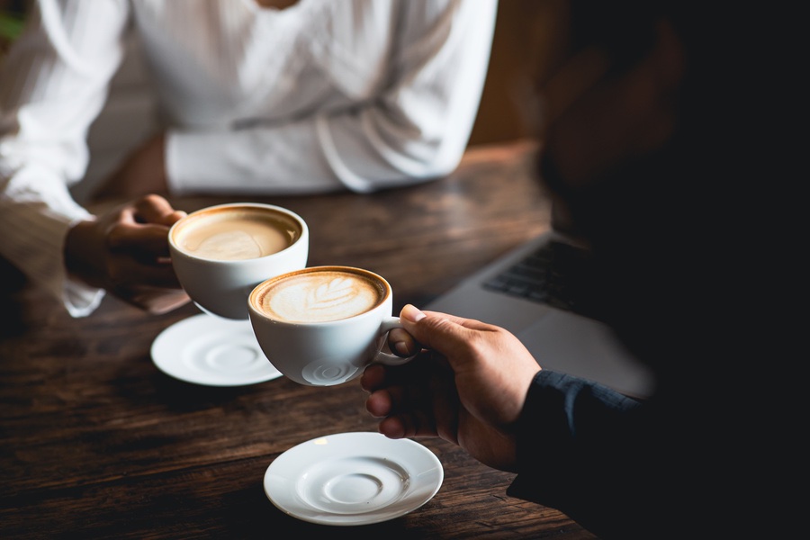 Close-up of a man and woman clinking a white coffee cup in a coffee shop. while talking at work Close-up of a man and woman clinking a white coffee cup in a coffee shop. while talking at work