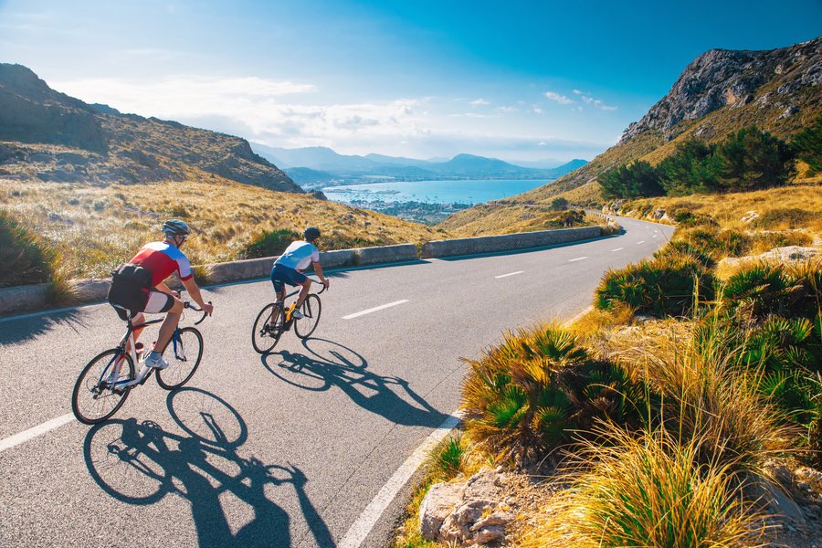Road cycling photo. Two triathlete train in beautiful nature. Sea and mountains in background. Alcudia, Mallorca, Spain Road cycling photo. Two triathlete train in beautiful nature. Sea and mountains in background. Alcudia, Mallorca, Spain